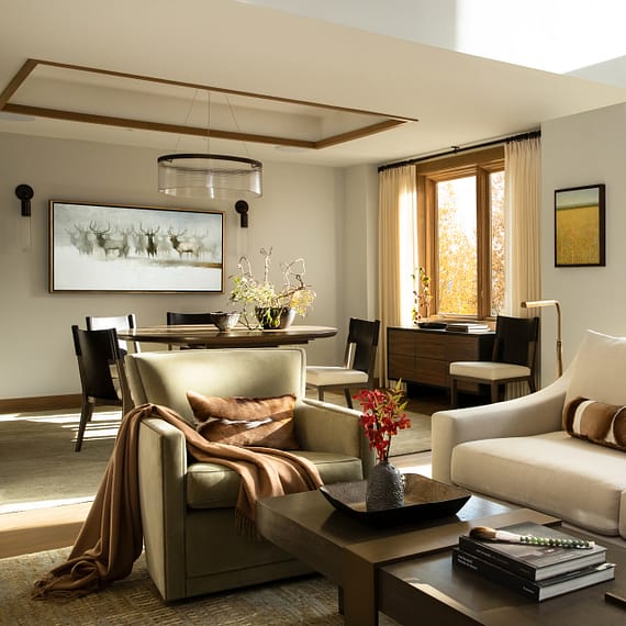 Four Seasons Residence living room with beige couch, green chair, and red flowers on coffee table. Photo by Tuck Fauntleroy