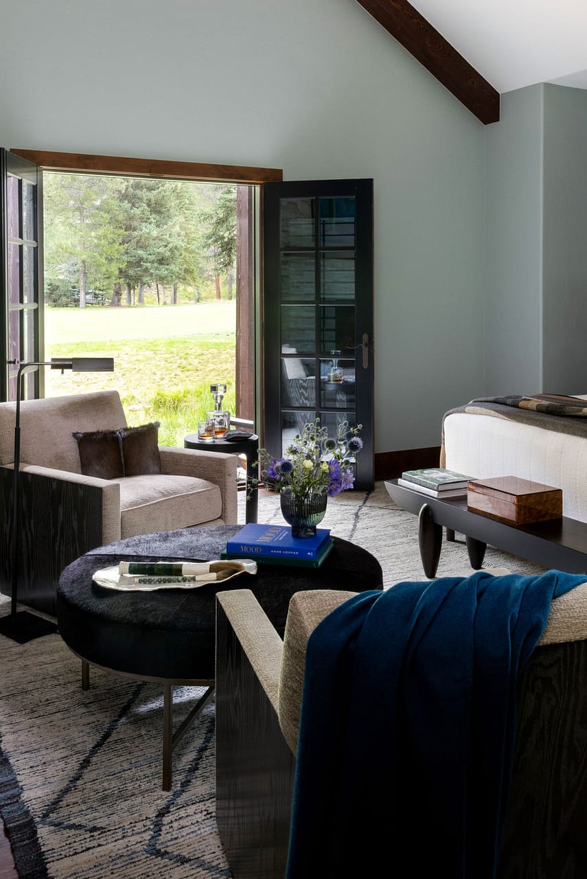 armchairs with coffee table and big open doors in bedroom